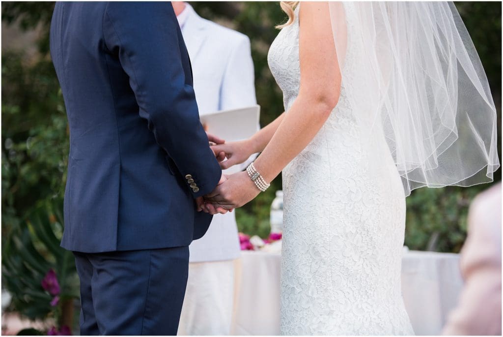 close up of bride and groom holding hands at wedding ceremony