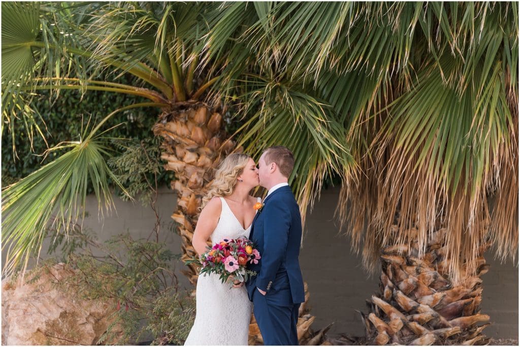 bride and groom kissing in front of palm trees