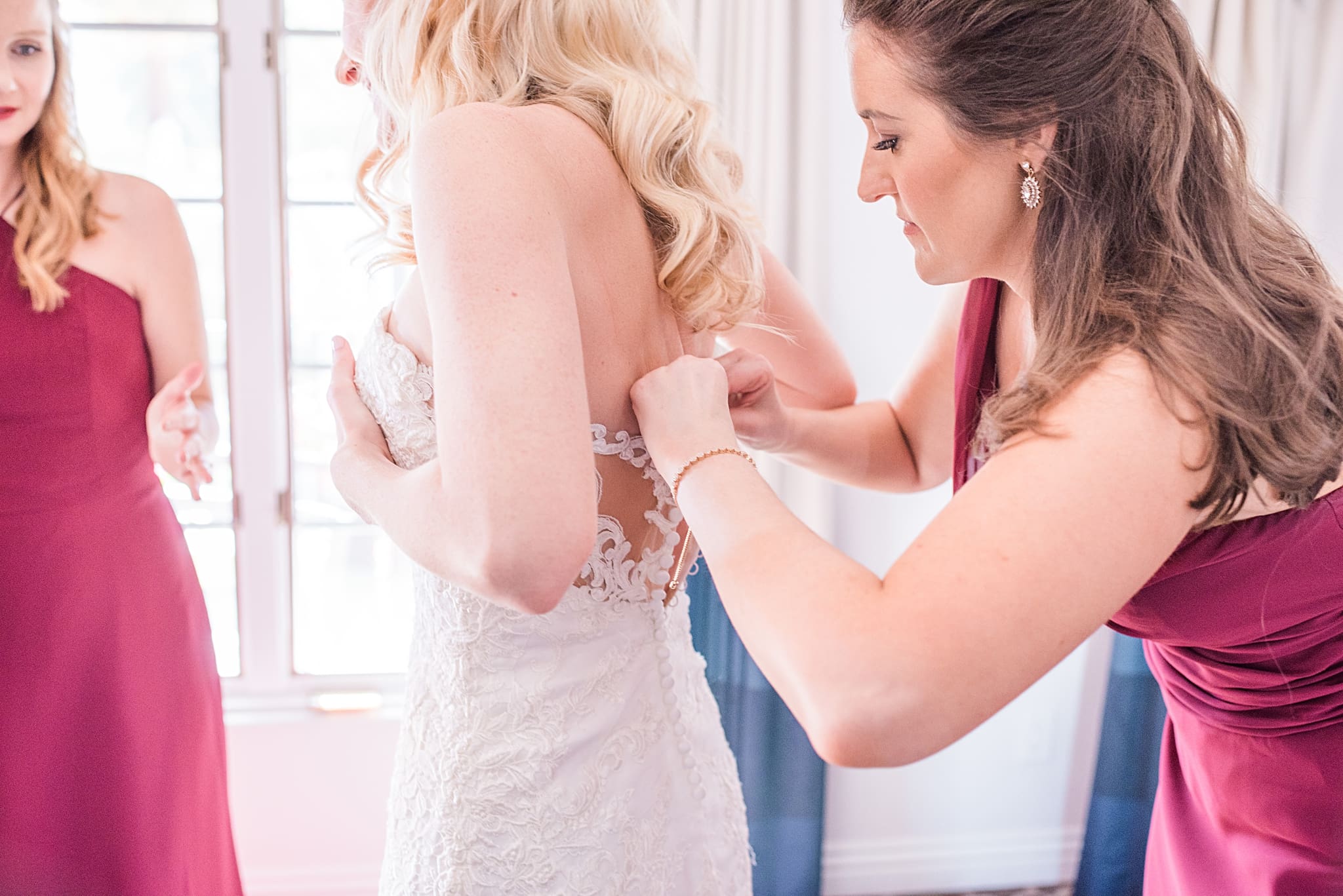 maid of honor buttoning up brides dress