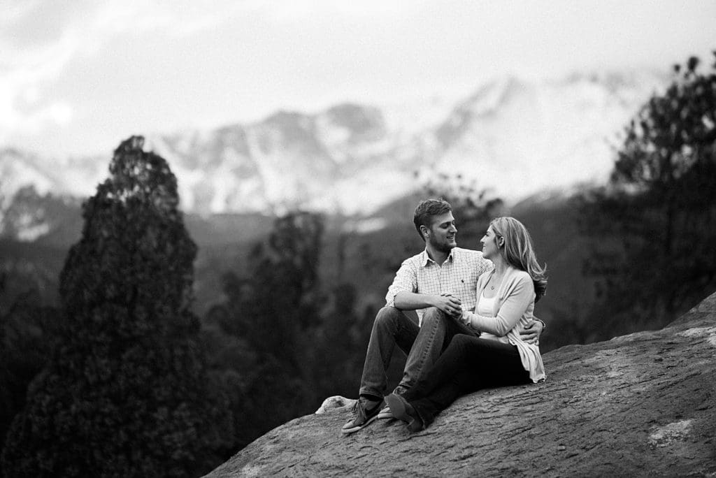 couple sitting on rock with pikes peak views