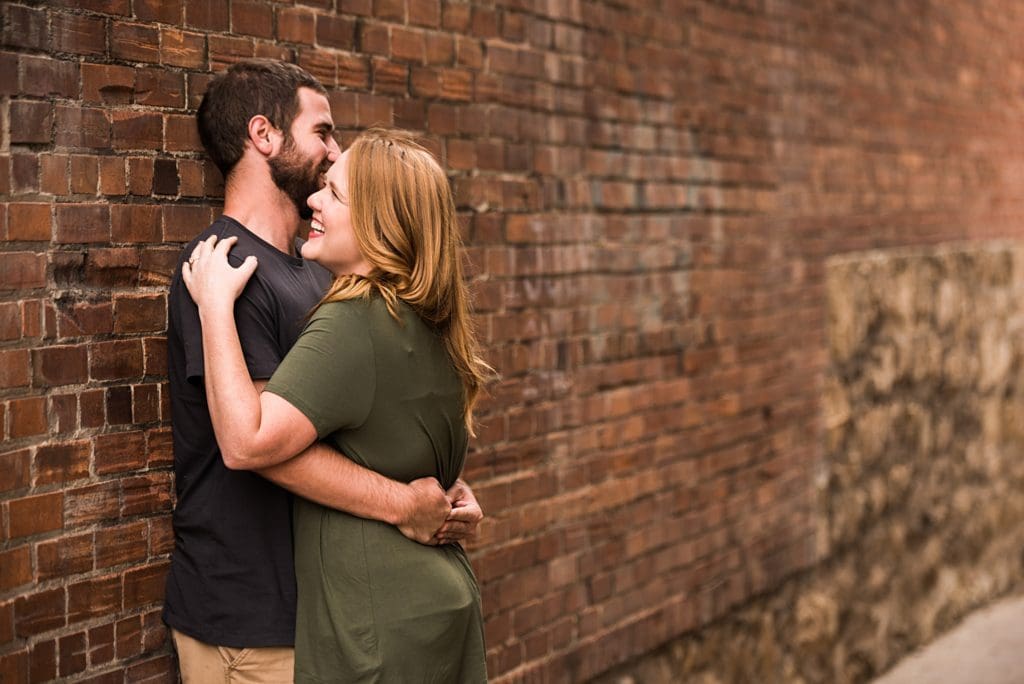 man and woman hugging by brick wall
