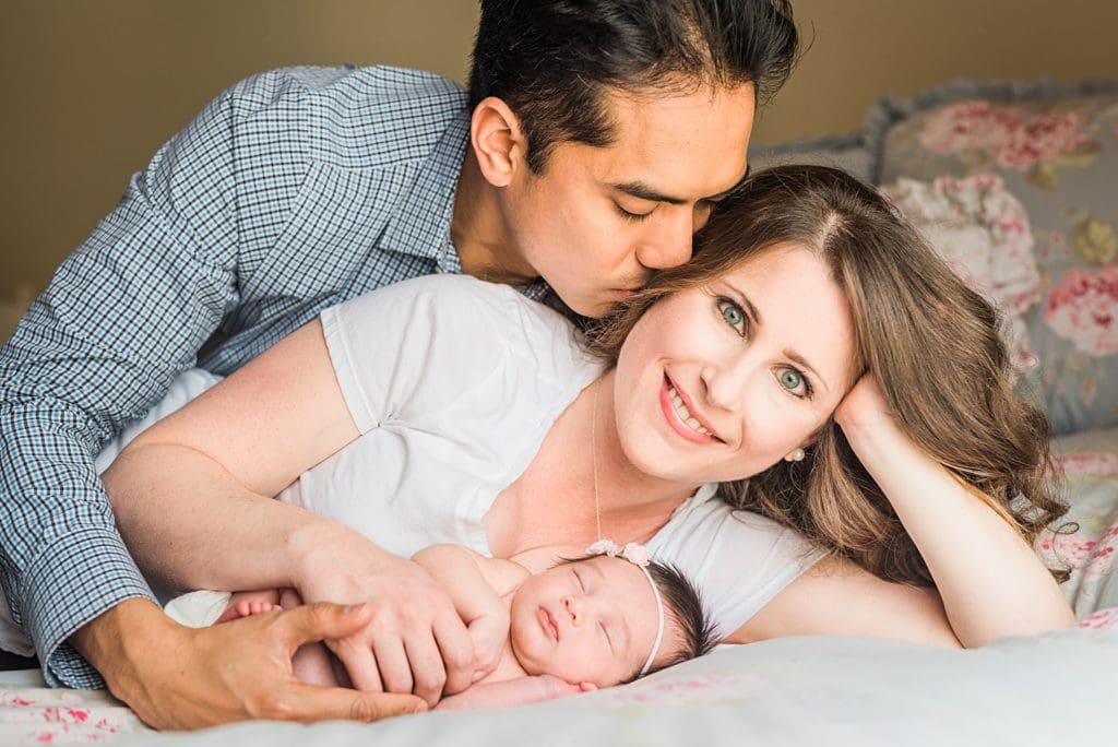 new father kissing wife with newborn