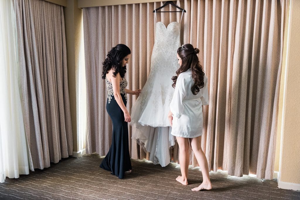 bride with sister looking at wedding gown