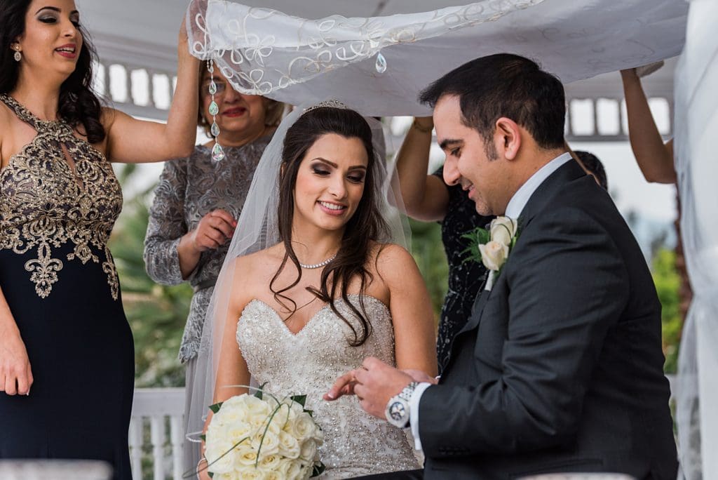 groom putting ring on brides fingers