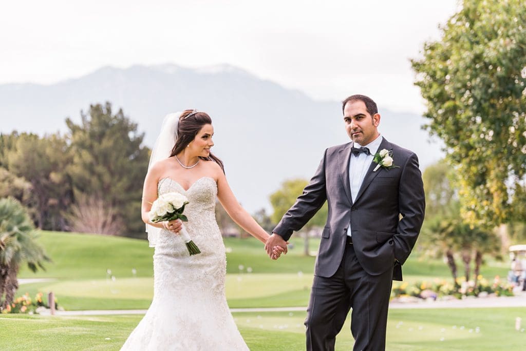 bride and groom holding hands on the golf course