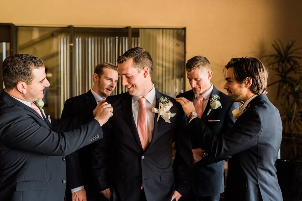 groomsmen helping groom get dressed
