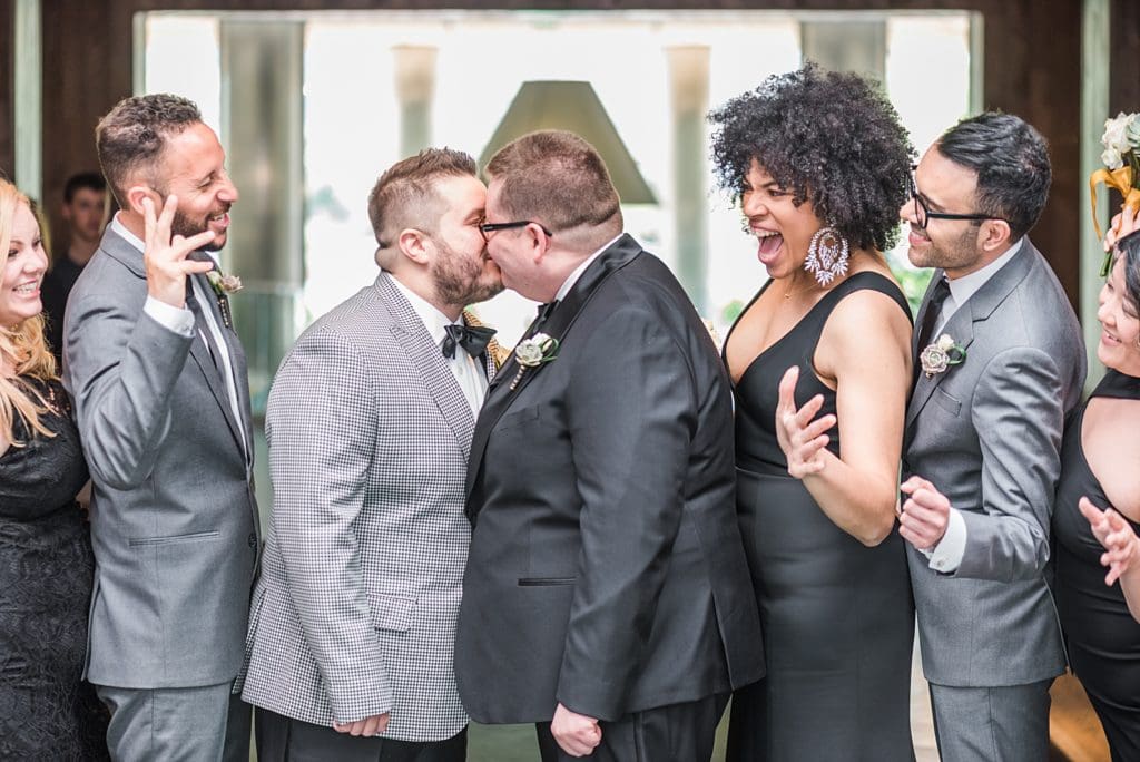 grooms kissing with their wedding party