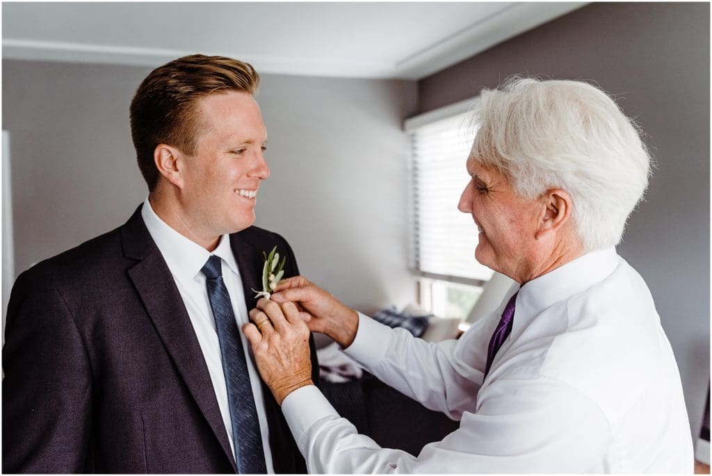 father of the groom pinning boutonniere on groom