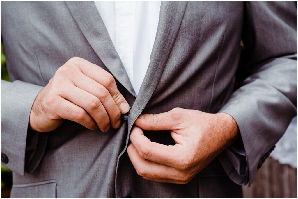 groom buttoning up his jacket