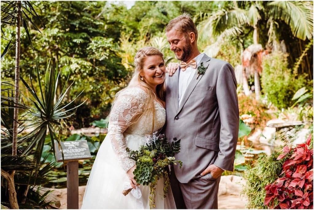 bride and groom laughing together in a botanic garden