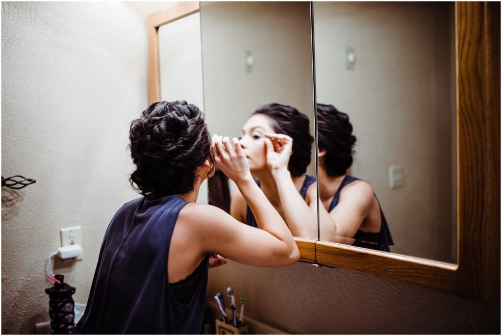 bride applying eyelashes in the mirror