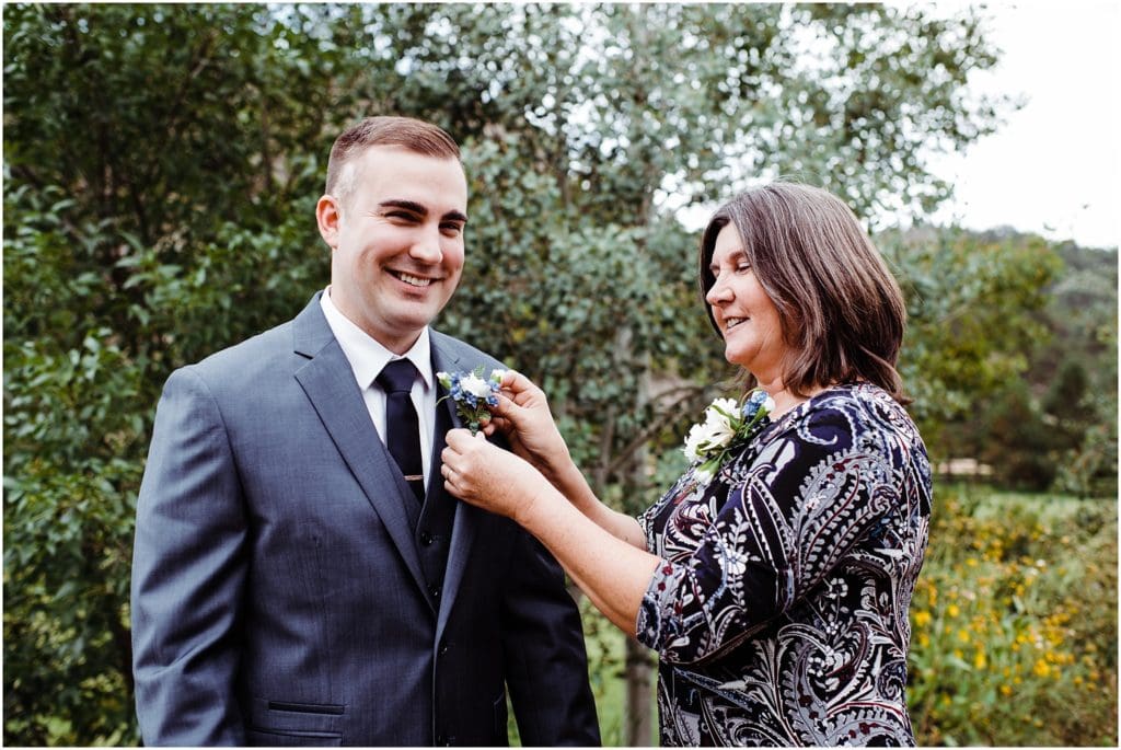 mother of the groom pinning boutonniere on 