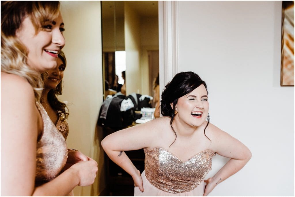 bridesmaids laughing as bride gets ready