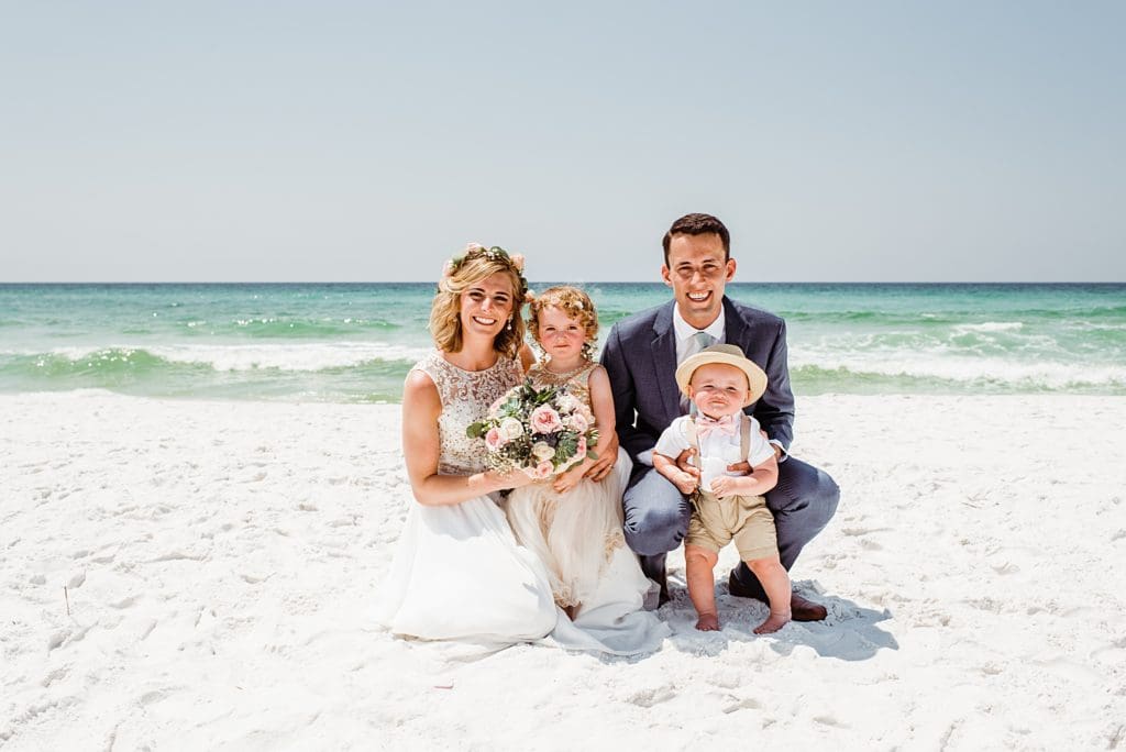 bride and groom with flower girl and ring bearer on the beach