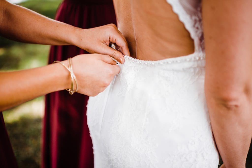 bridesmaids helping bride get dressed outside