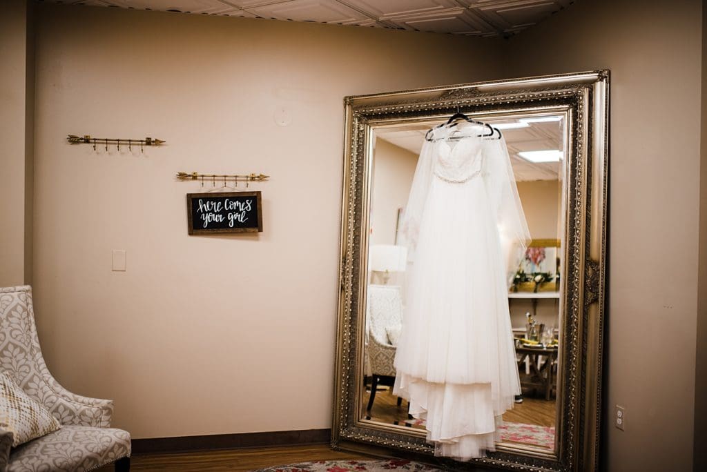 wedding dress hanging up on large mirror