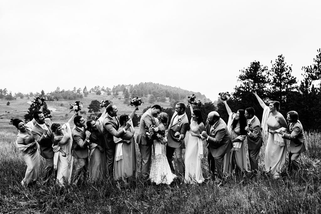 black and white photo of wedding party cheering on bride and groom