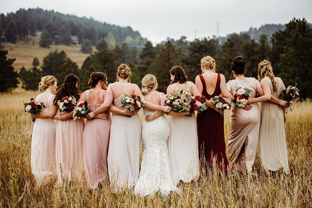 bridal party with arms wrapped around each other from behind