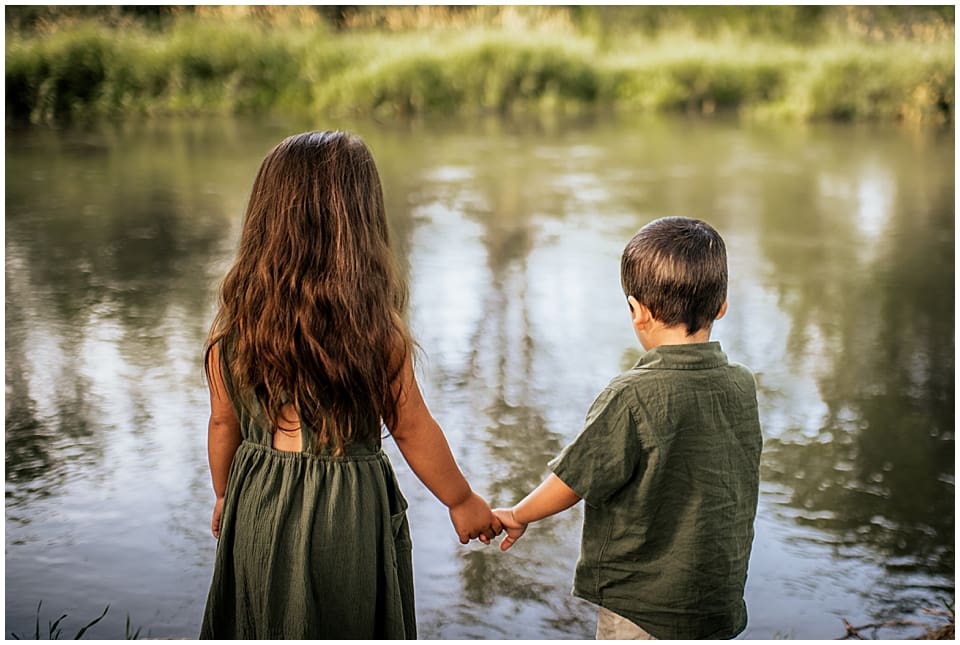 two kids holding hands next to the river