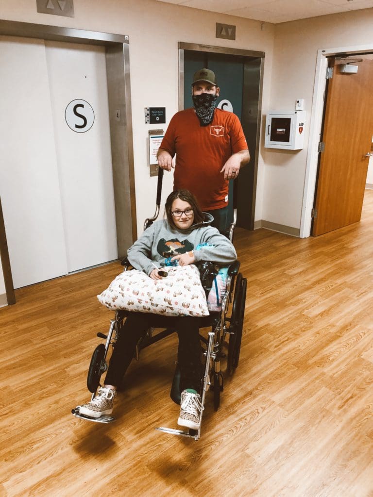 dad pushing teenager daughter in wheelchair after surgery
