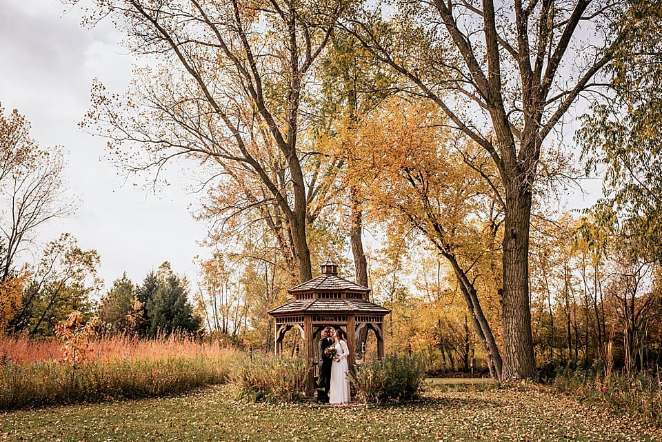 bride and groom in wood gazebo in the fall in wisconsin