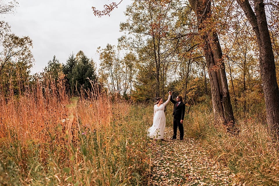 bride and groom dancing in the fall foliage