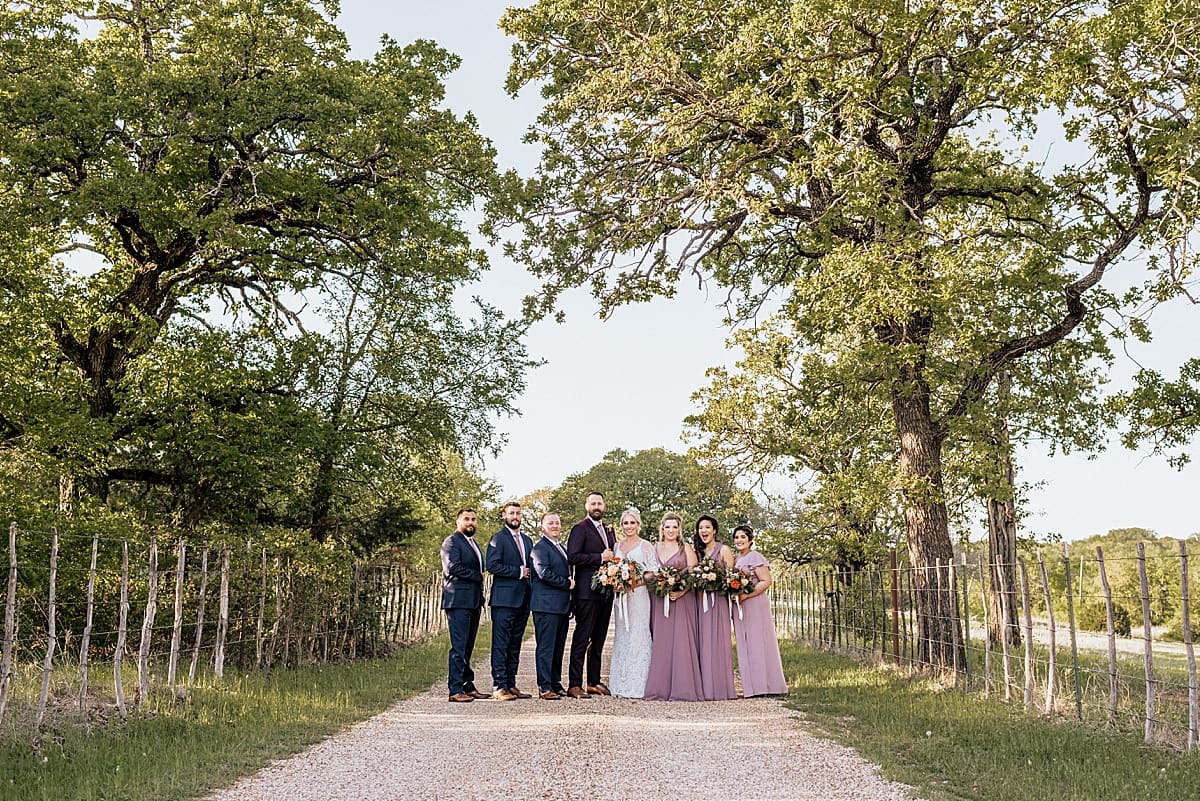 wedding party on a dirt road surrounded by trees