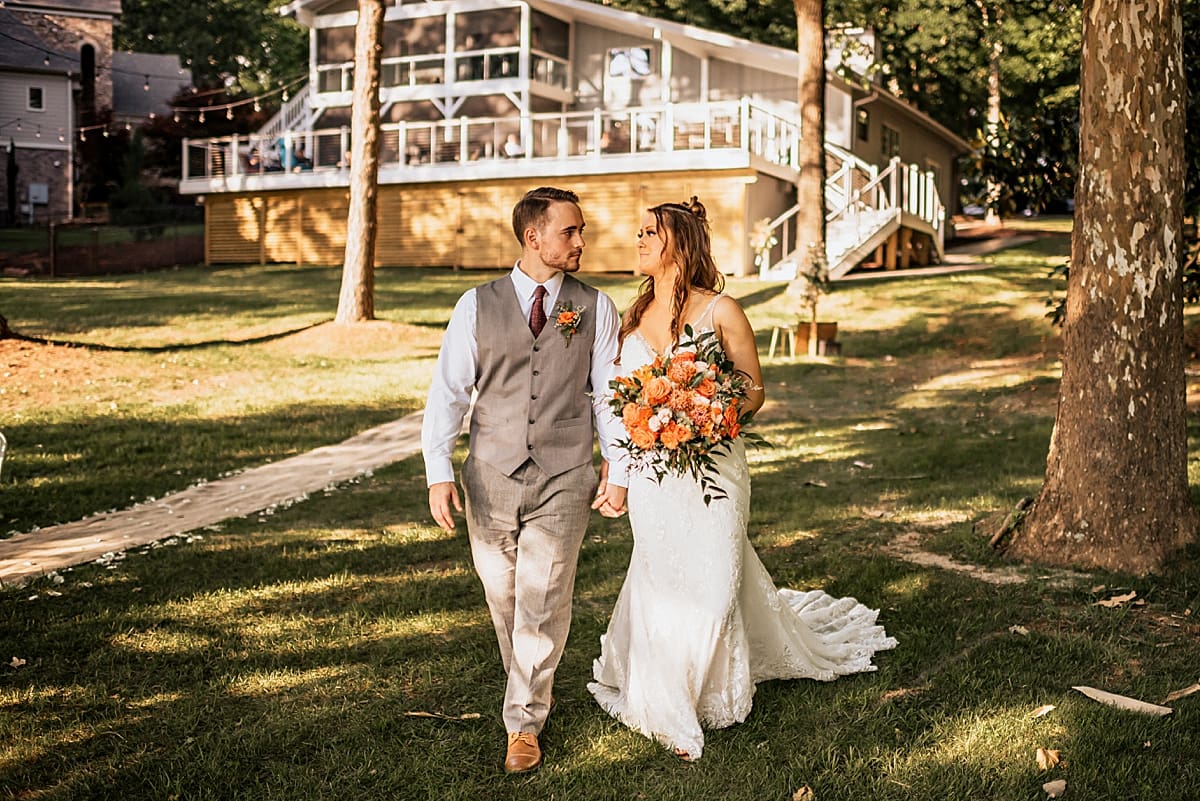 bride and groom walking in front of lake house