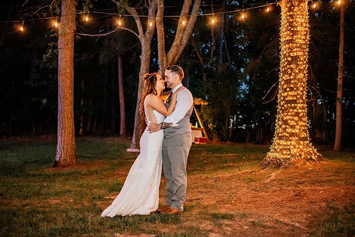 bride and groom kissing under string lights