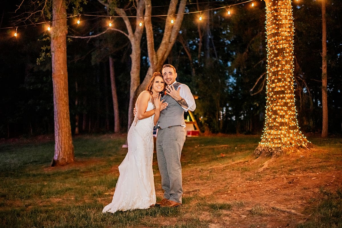 wedding couple showing off rings under string lights