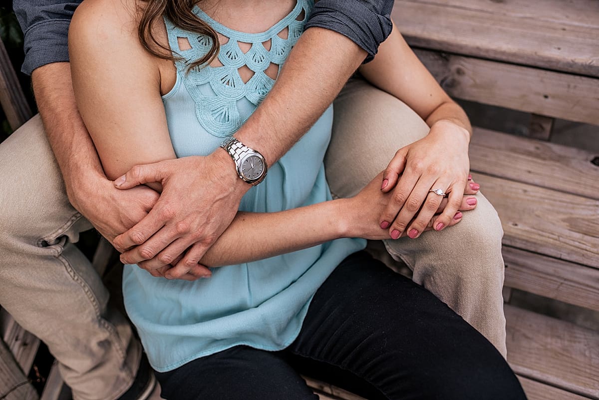 couple snuggling showing off engagement ring and watch