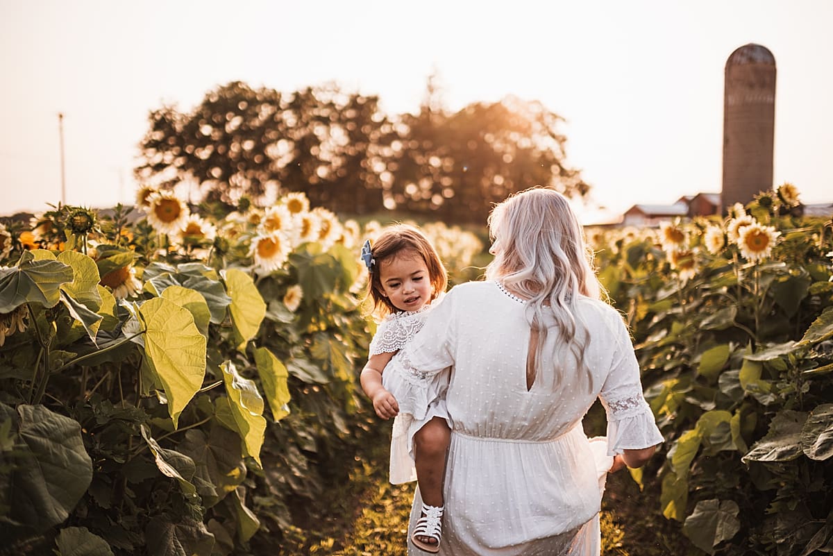 mom and toddler walking through a flower field