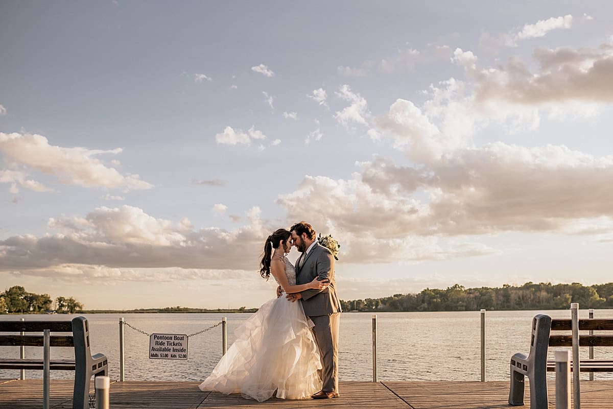 bride and groom at the end of the pier at the lake at sunset