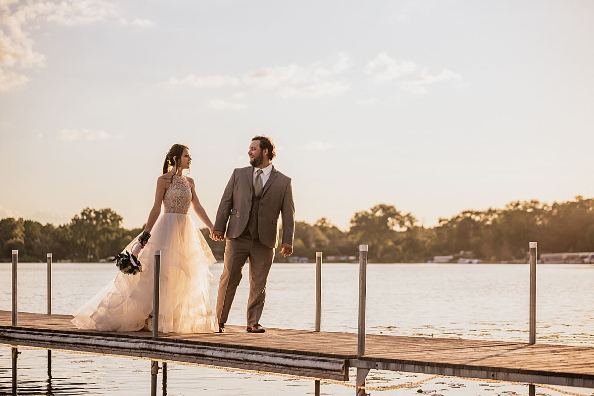 bride and groom at the end of the pier at the lake at sunset