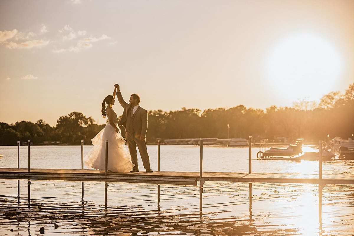 bride and groom dancing on the lake pier at sunset