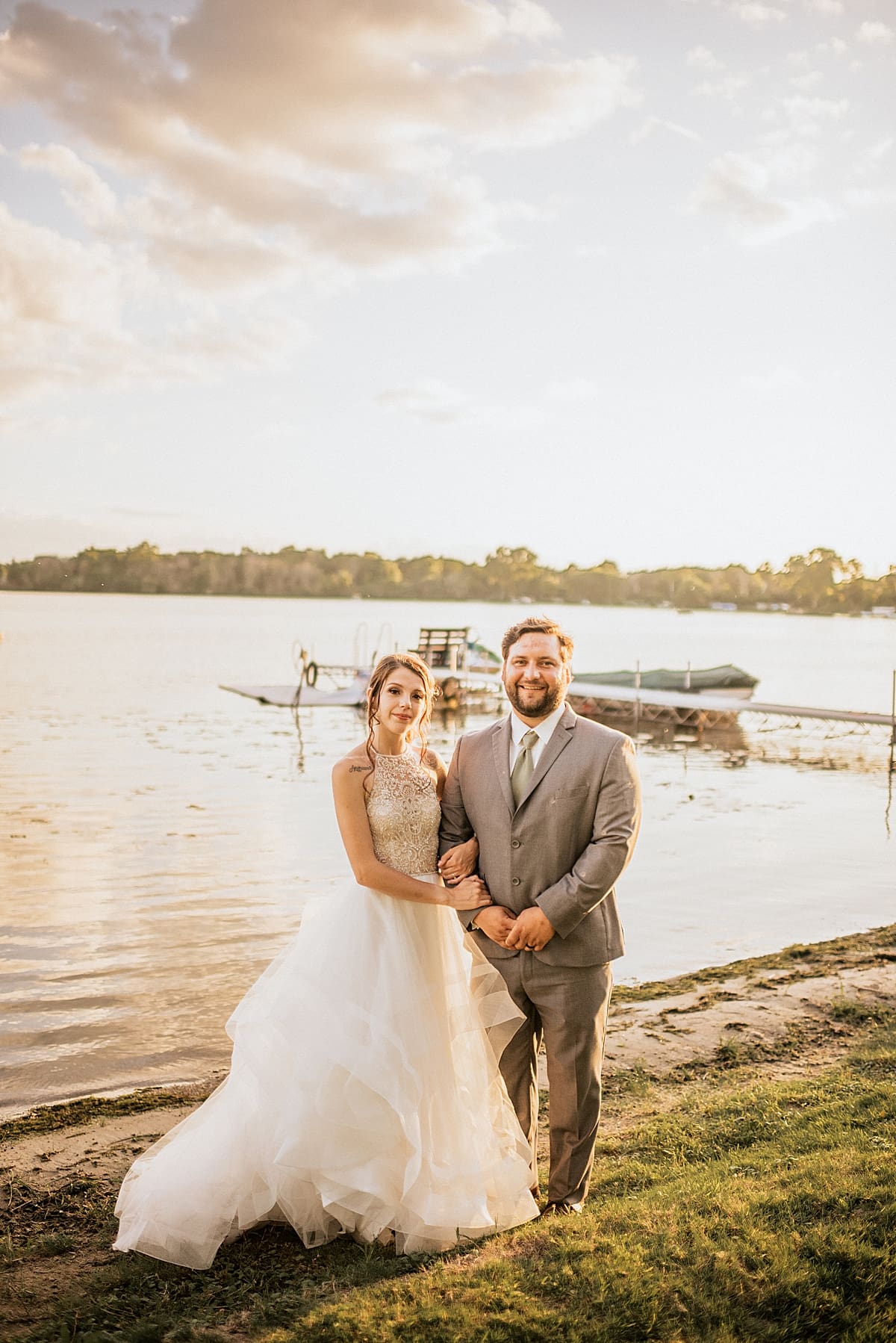 bride and groom in front of the lake at sunset
