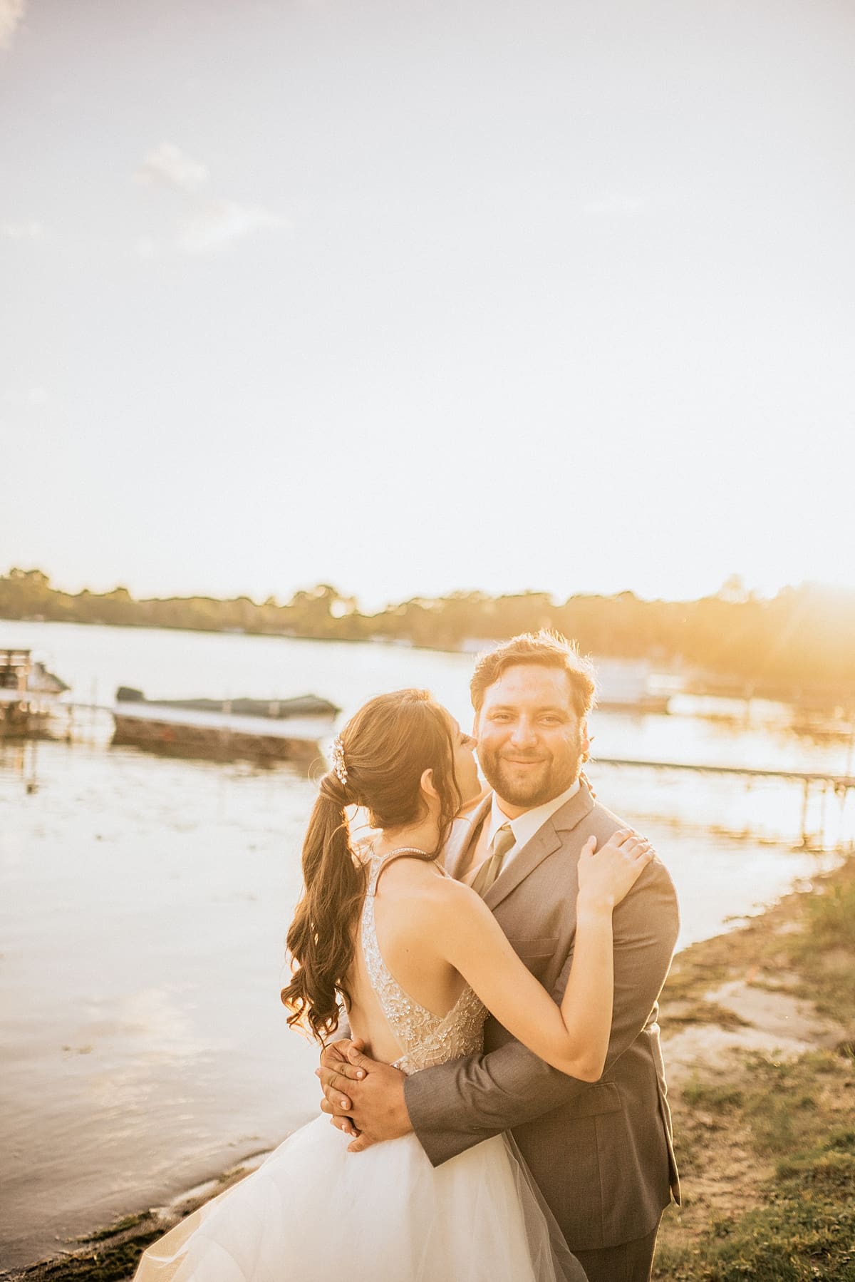 bride and groom in front of the lake at sunset
