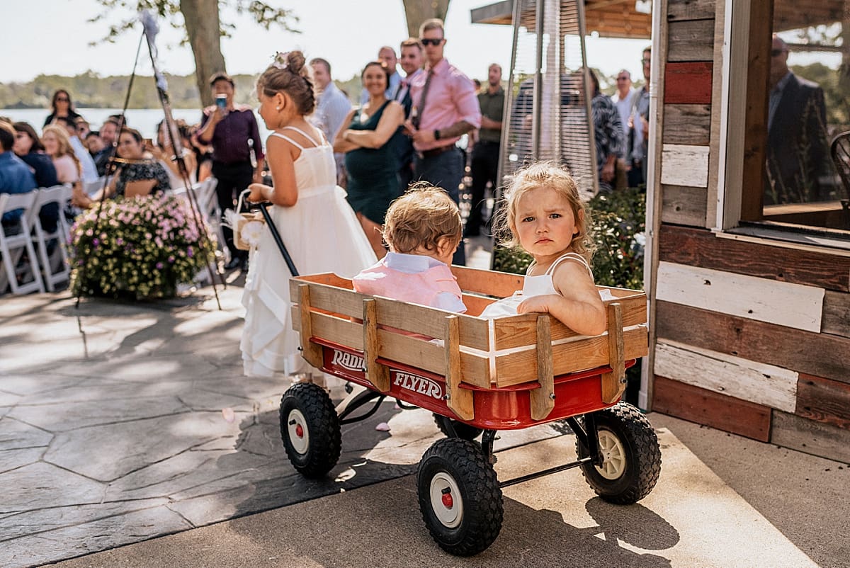flower girl pulling ring bearer in a red wood wagon