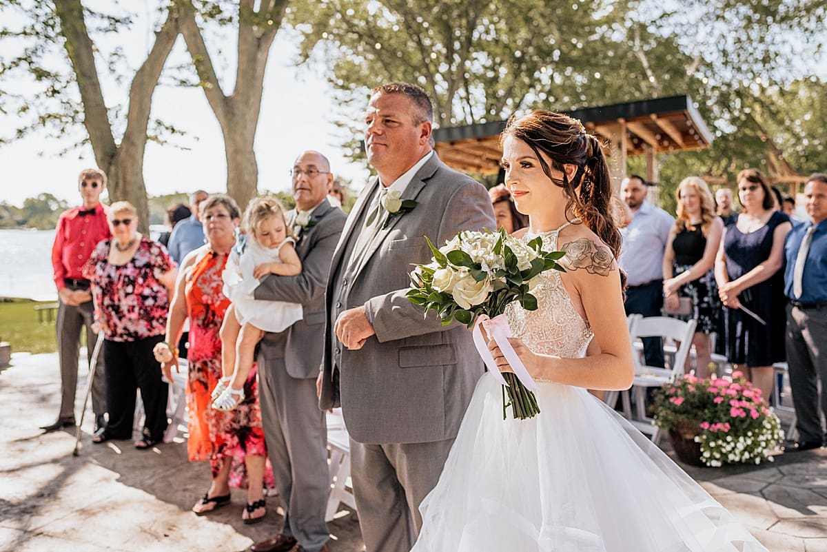 father of the bride walking bride down the aisle at outdoor ceremony