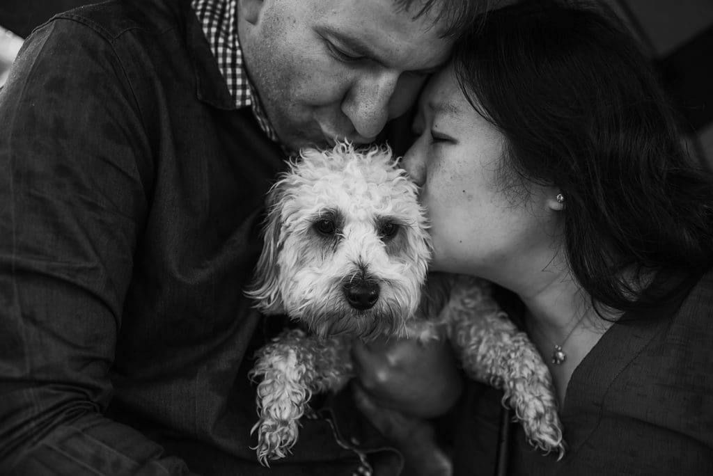 couple kissing their dog during engagement session