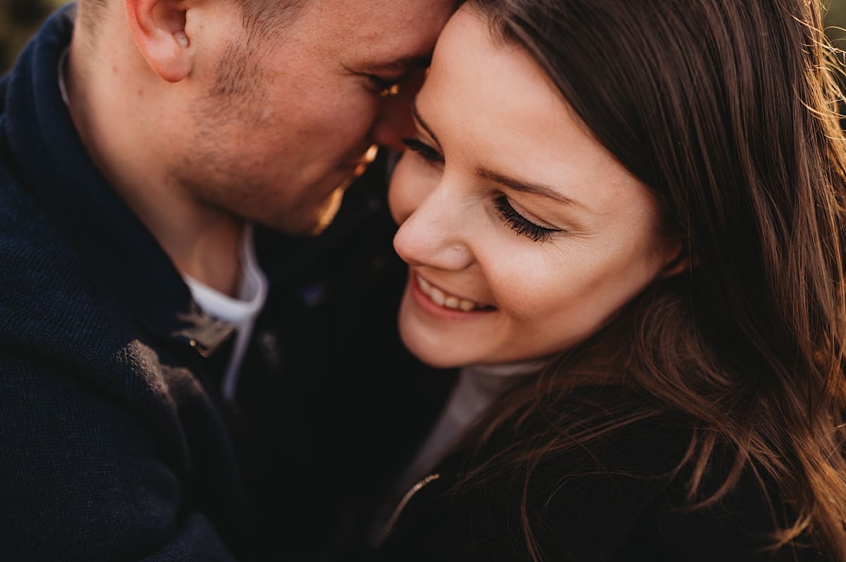 man whispering in woman's ear engagement session