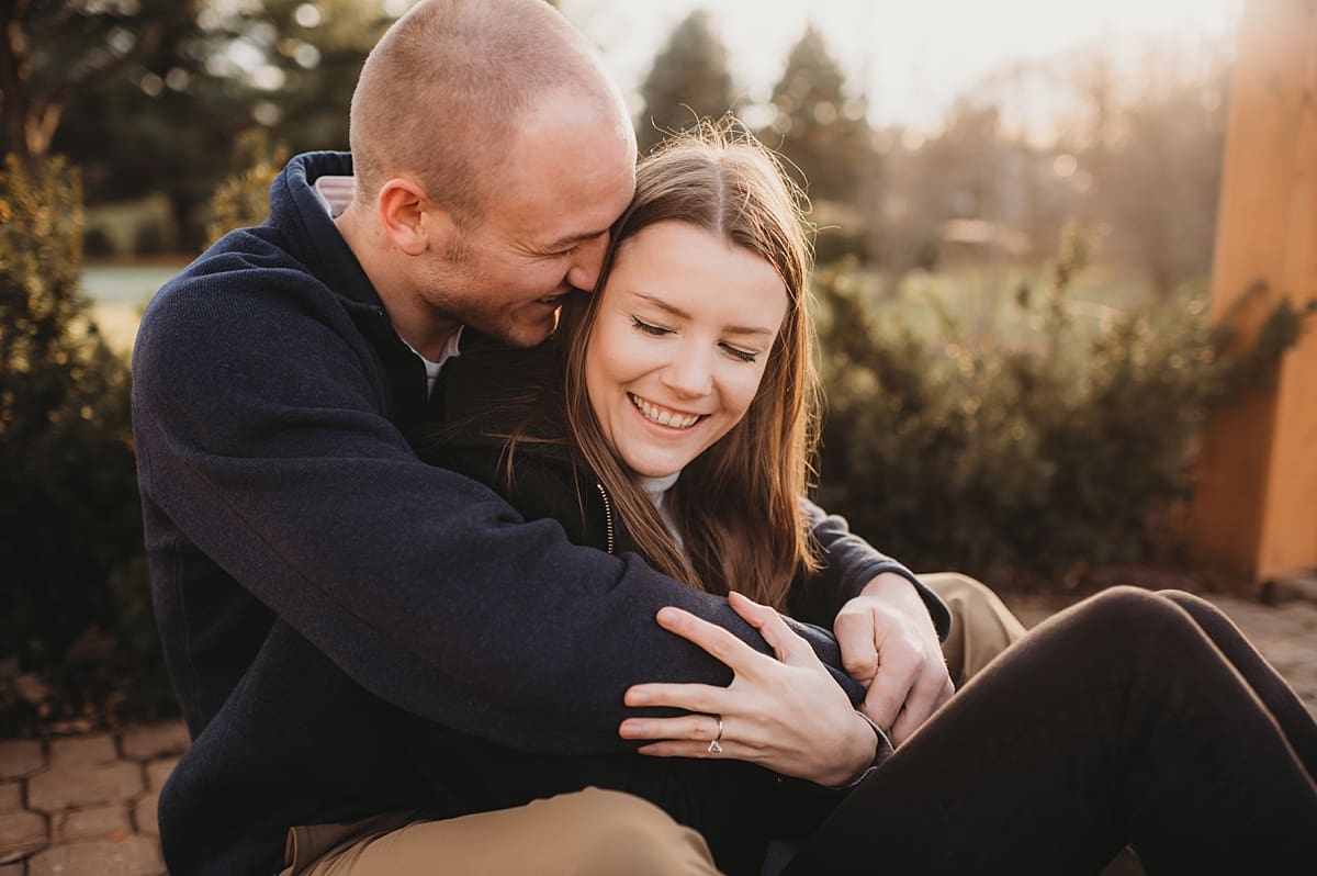 woman sitting between man's leg and snuggling engagement poses