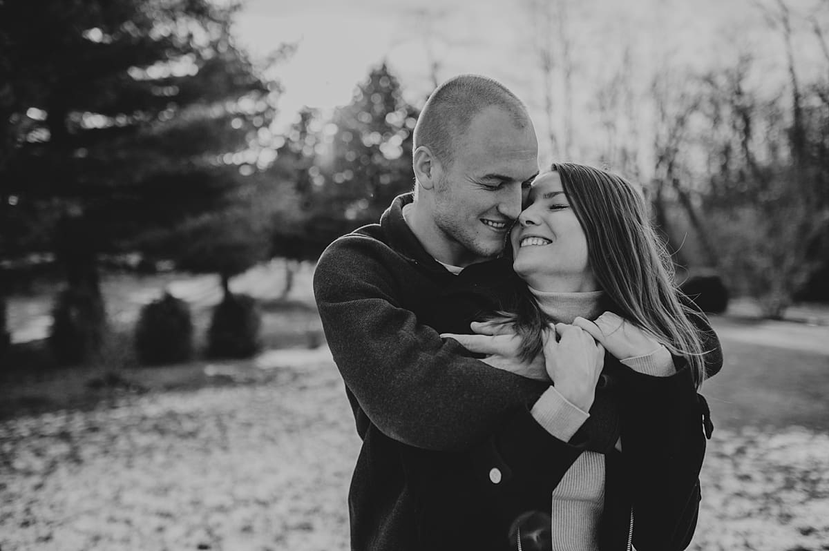 black and white engagement photo of couple snuggling