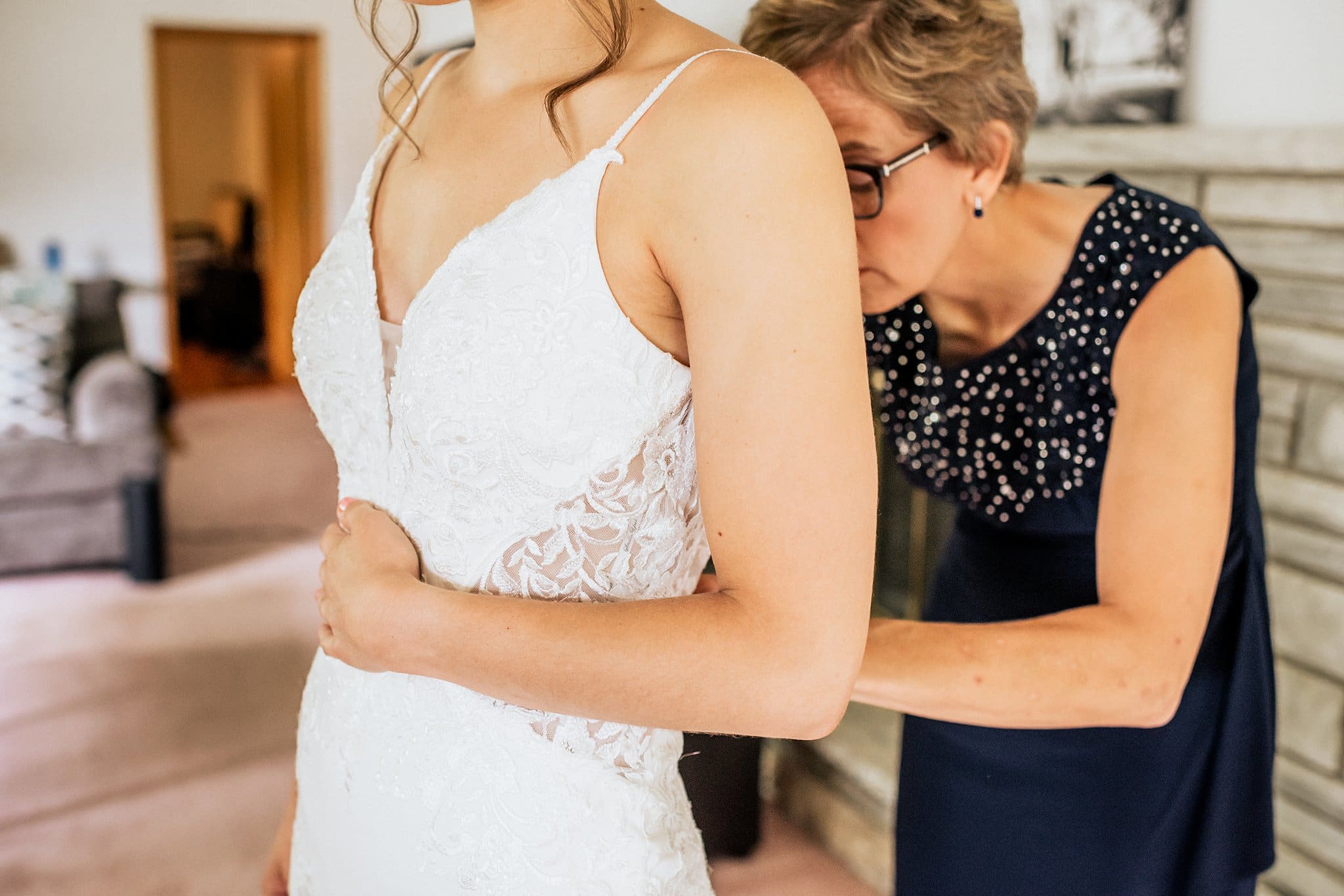 mother of the bride helping daughter get ready for wedding