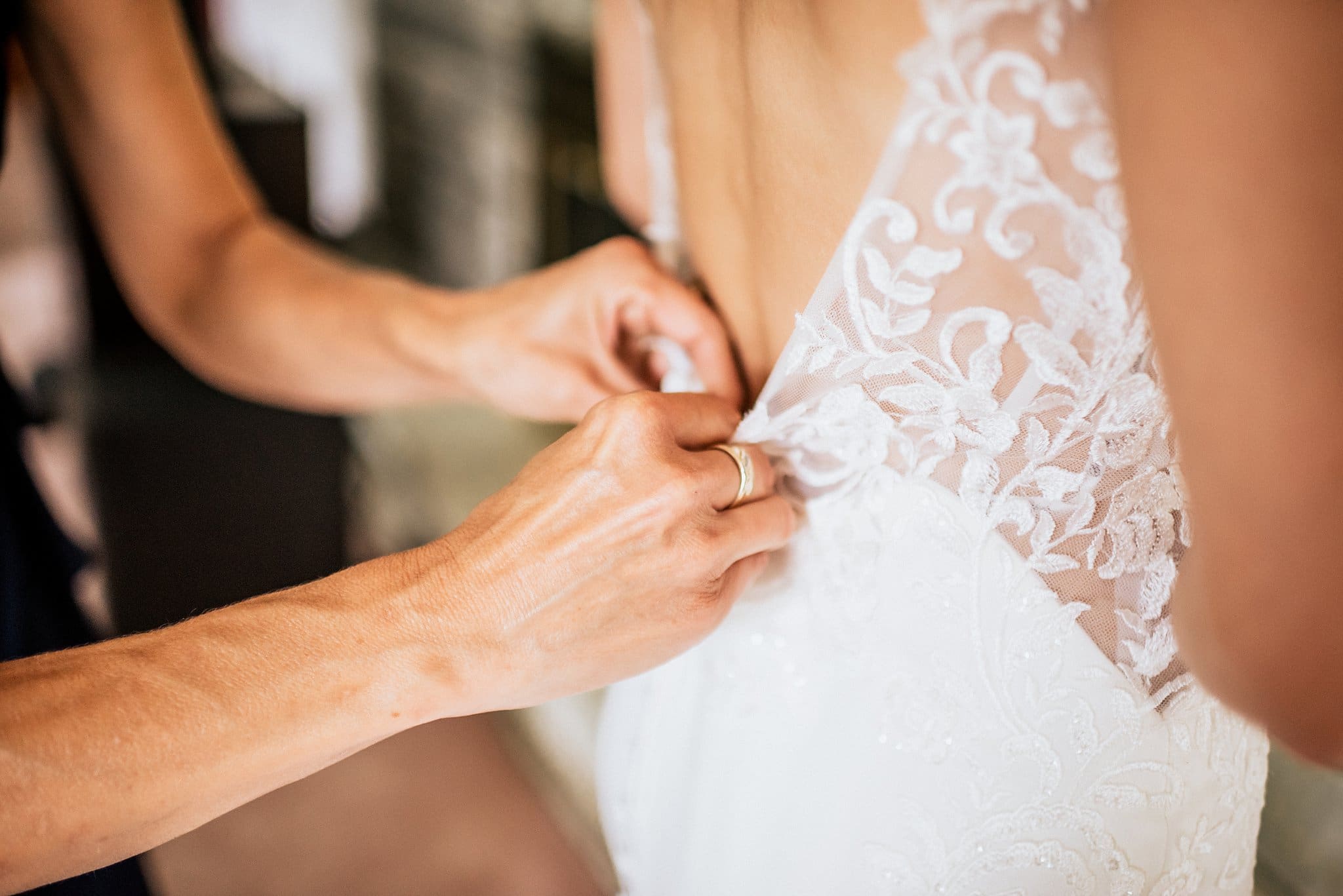 mother of the bride helping daughter get ready for wedding