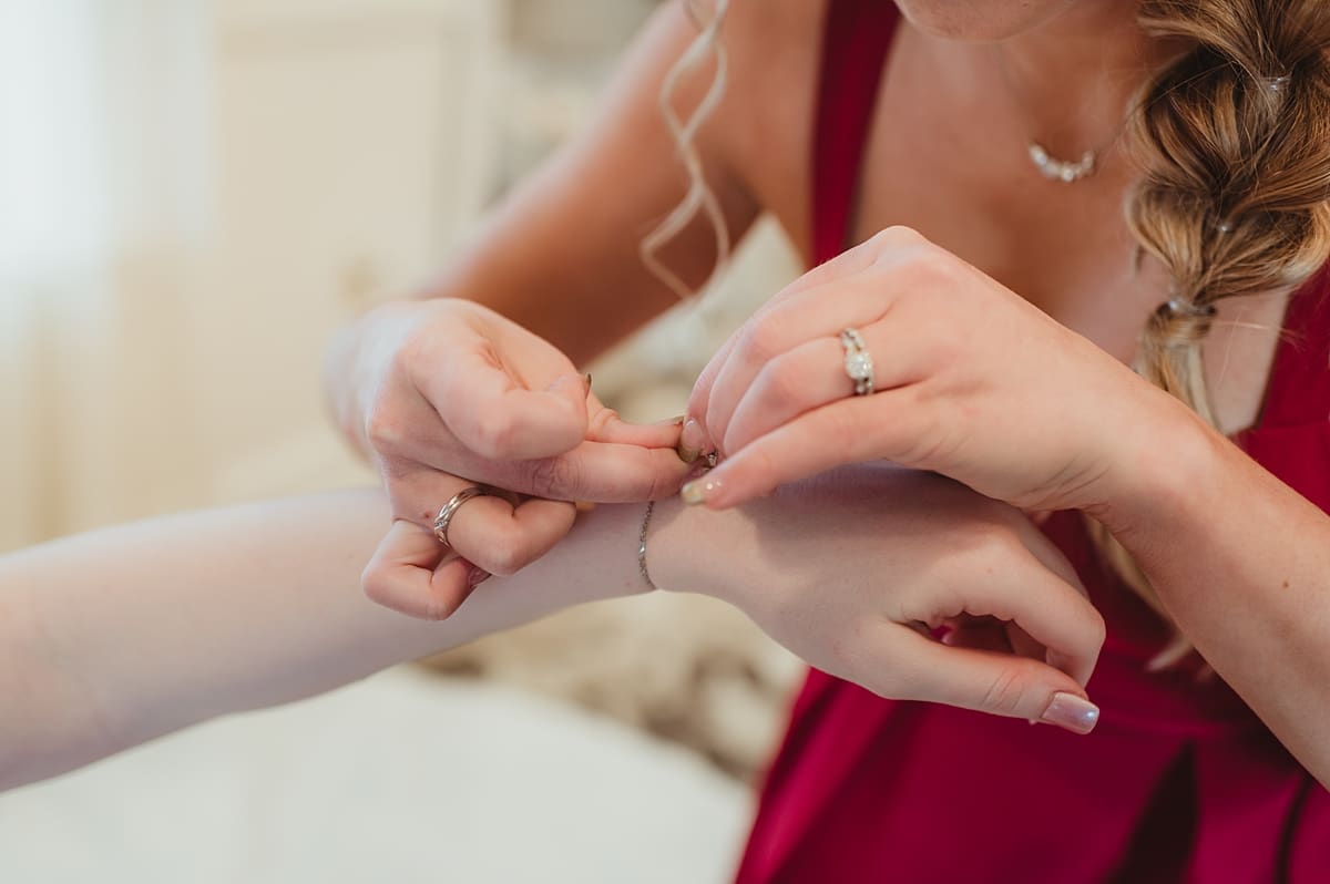 bridesmaid putting bracelet on bride