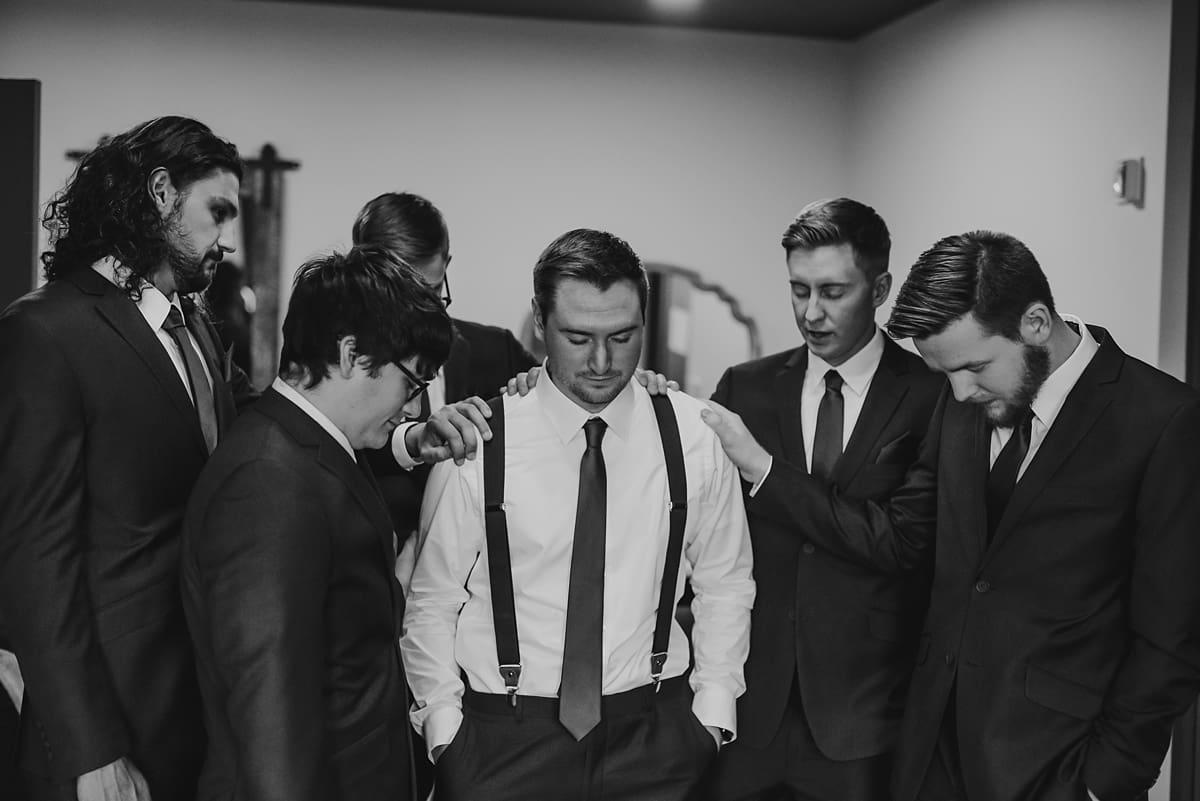 groomsmen praying over groom