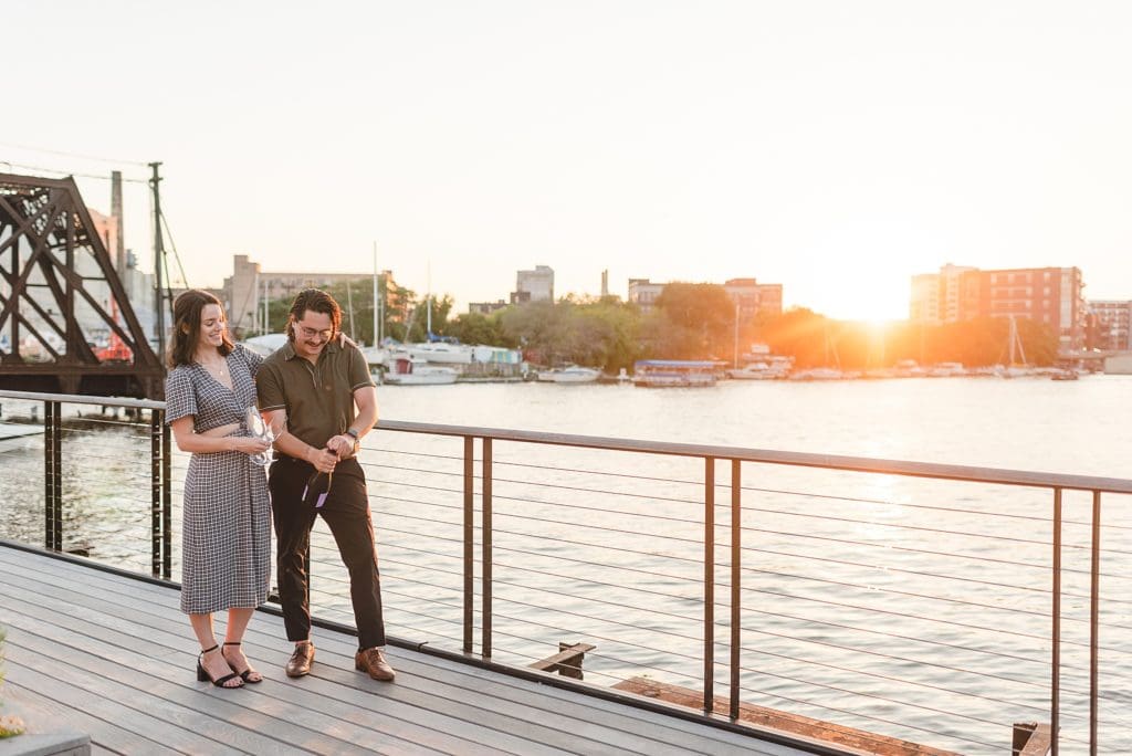 popping champagne at engagement session at sunset