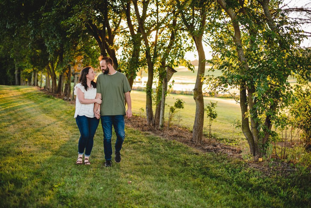 engagement photos couple walking through trees 