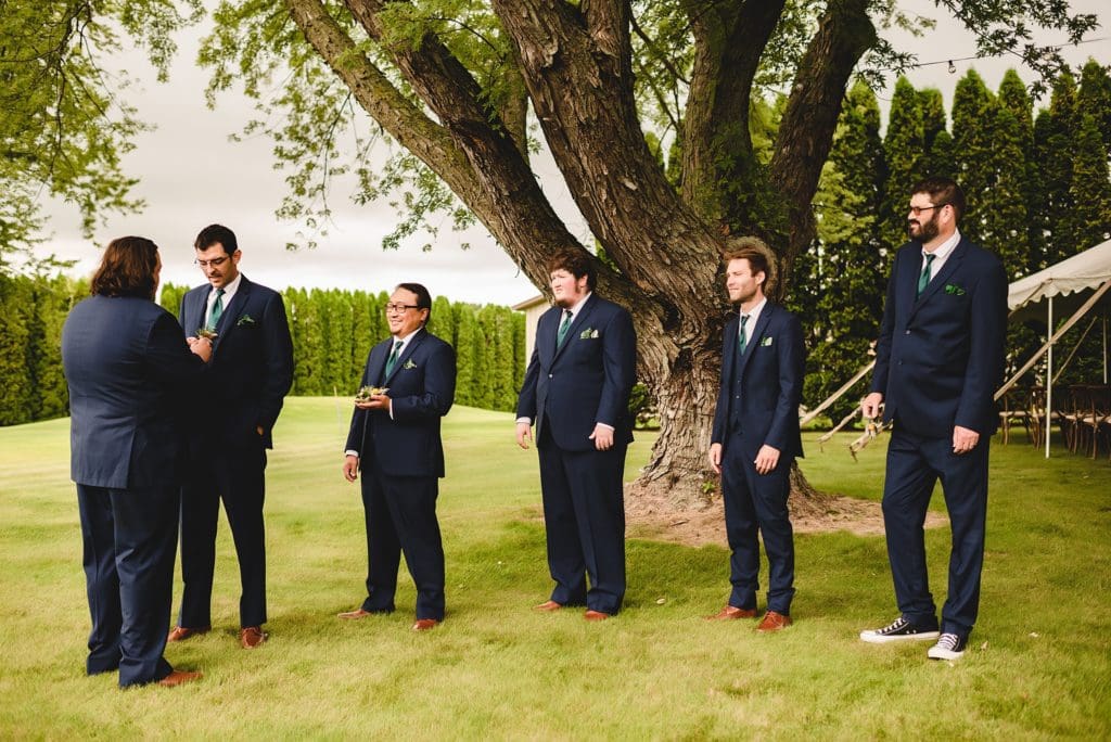 groom and groomsmen putting on boutonnieres 